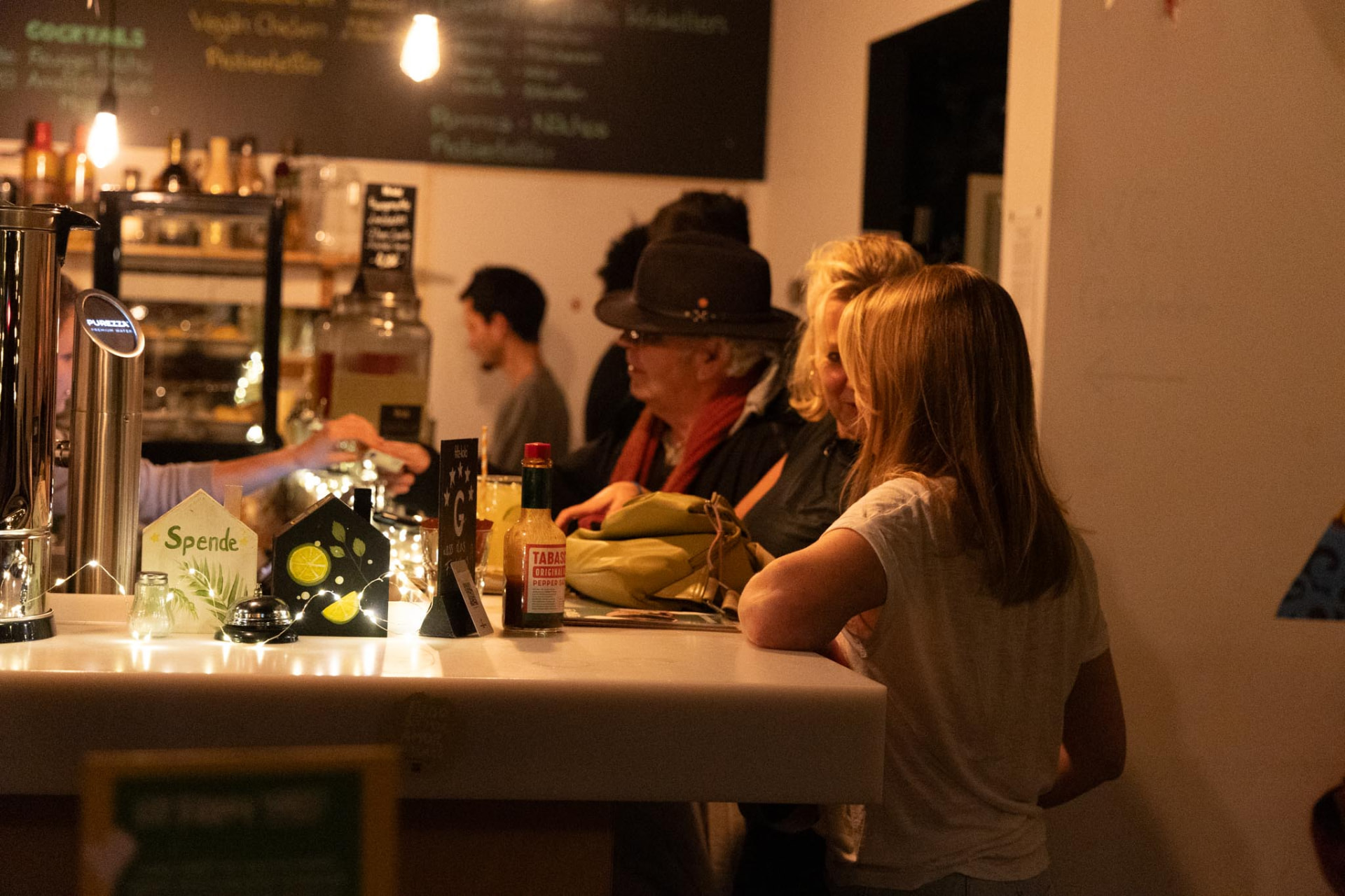 Gäste stehen im warmen Licht an der Bar