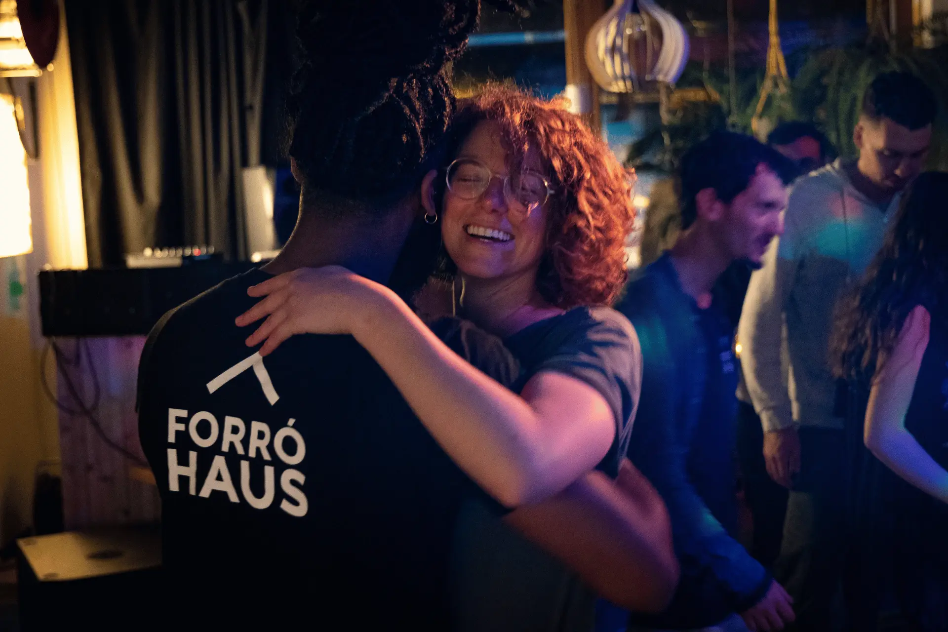 Zwei Gäste umarmen sich lachend beim Tanzen am Abend
