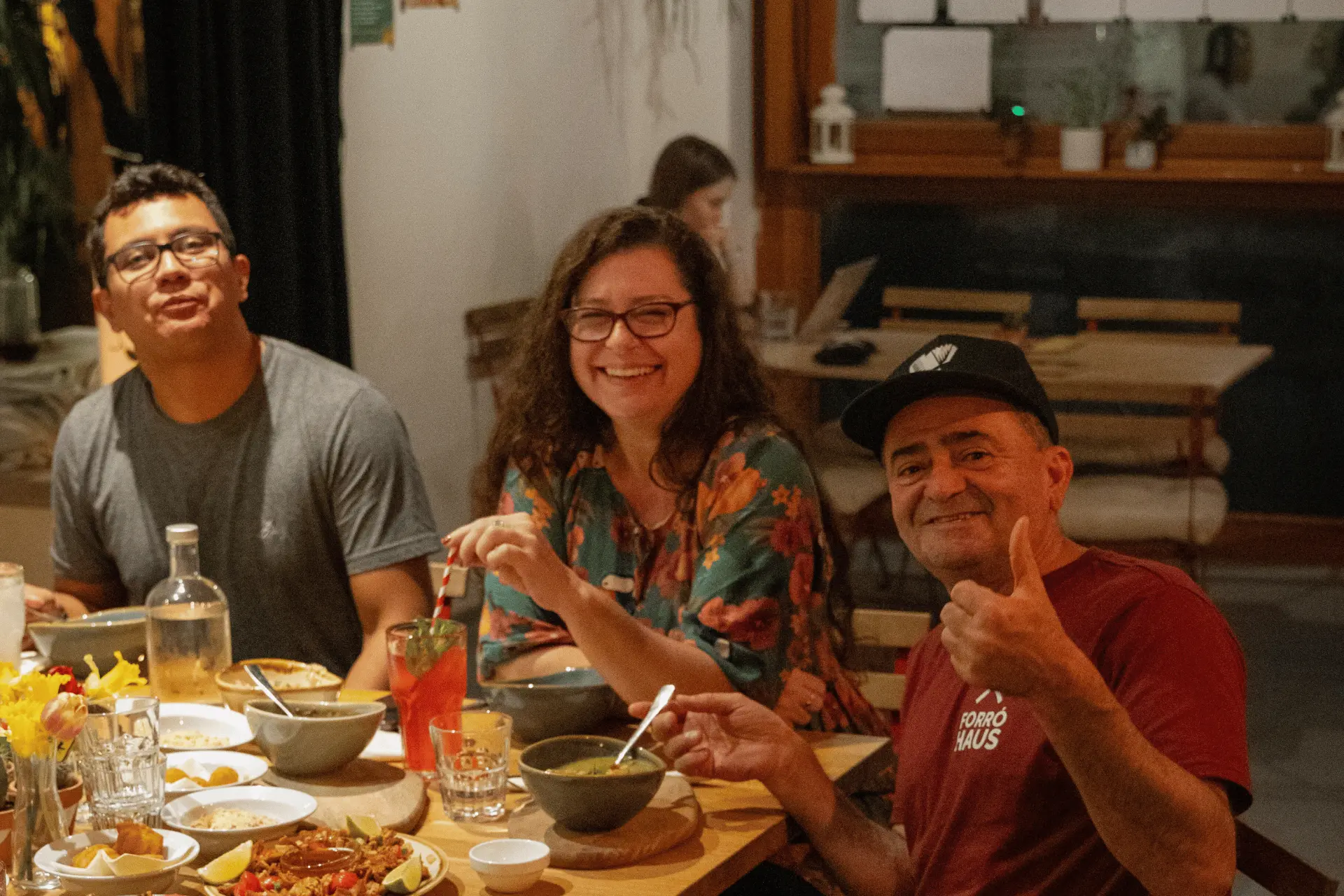 Drei Gäste am gedeckten Tisch mit brasilianischen Gerichten